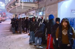Uma fila de pessoas entusiásticas do Boxing Day, aguarda a abertura do espaço Best Buy, nas ruas Bay e Dundas, apesar da neve que caía na cidade de Toronto. CityNews.