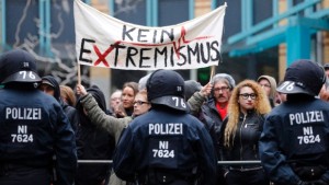 As forças policiais protegem os Salafistas contra os manifestantes que mostram uma faixa que diz "Nenhum Extremismo", durante uma manifestação dos europeus patrióticos contra a islamização do Ocidente, ou PEGIDA, e Salafistas, em Wuppertal, Alemanha - 14 de março de 2015. (Frank Augstein/The Associated Press)