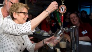 A primeira-ministra Kathleen Wynne tira um pouco de cerveja durante a campanha eleitoral de há quase um ano atrás. O orçamento incluirá medidas para permitir a venda de cerveja em algumas mercearias do Ontário. (Frank Gunn / Canadian Press