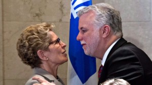 A primeira-ministra do Ontário, Kathleen Wynne e o primeiro-ministro do Quebec, Philippe Couillard, abraçam-se depois de assinarem um acordo sobre o meio ambiente – 13 de abril, 2015, em Quebec City. (Jacques Boissinot/The Canadian Press)