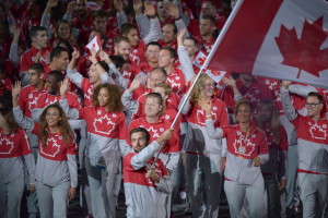 O canoísta canadiano, Mark Oldershaw, transporta a bandeira do Canadá ao lado de companheiros de equipa durante o desfile das nações na cerimónia de abertura dos Pan Am Games 2015 de Toronto no Rogers Centre na sexta-feira, 10 de julho de 2015. (The Canadian Press / Frank Gunn)