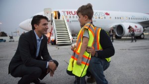 O líder do Partido Liberal Justin Trudeau conversa com Olivier Moreira, 6, que quebrou o braço a fazer piruetas, e o seu pai Fernando, antes de embarcar no seu avião para voar para Winnipeg, 29 de setembro, 2015, em Toronto. THE CANADIAN PRESS/Paul Chiasson