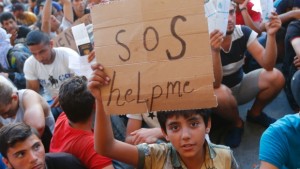 Uma criança segura um cartaz onde se pode ler "SOS help me" do lado de fora da estação ferroviária em Budapeste, Hungria - 2 de setembro de 2015. (Laszlo Balogh / Reuters)