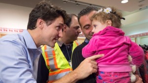O primeiro-ministro canadiano Justin Trudeau fala com uma jovem ao cumprimentar uma família de refugiados sírios durante a sua chegada ao aeroporto International Pearson, em Toronto, na sexta-feira, 11 de dezembro de 2015. (Nathan Denette / The Canadian Press)