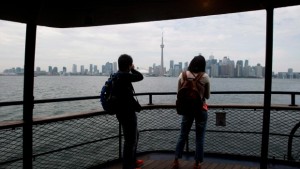 Passageiros fotografam o horizonte da cidade de Toronto, a partir do ferry, em direção às ilhas de Toronto, em Toronto. (The Canadian Press / Nathan Denette)