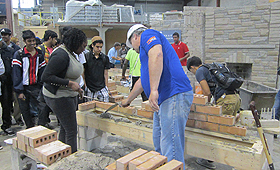Jovens aprendem a técnica de assentar tijolo