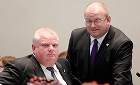 Mark Towhey, consultor de política do presidente Rob Ford, fala com ele durante o debate do conselho municipal do plano “One City” de Karen Stintz, a 11 de julho de 2012. (The Globe and Mail/Peter Power).