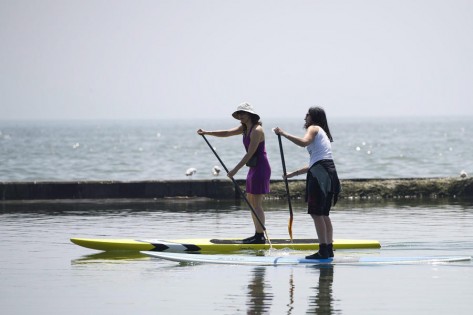 Duas mulheres usam paddleboards no Lago Ontário, Toronto - 31 de maio de 2011. (The Canadian Press / Nathan Denette)