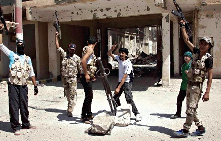 Rebeldes sírios festejam enquanto preparam lançamento de um rocket contra forças leais ao presidente Bashar al-Assad