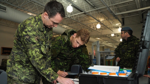 Os capitães farmacêuticos Wayne Clark e Adam Calabrese, preparam uma lista nominal dos membros da DART, prontos para ajudar as Ilhas Filipinas, que foram devastadas pelo tufão Haiyan - CFB Trenton, Ontário, 11 de novembro de 2013. (Canadian Forces Combat Camera / Cpl. Darcy Lefebvre)