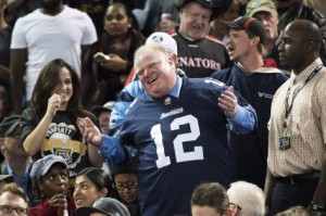 Rob Ford ri com os fãs, durante a final da Divisão Este (CFL) que envolveu os Toronto Argonautas e os Hamilton Tiger-Cats.  THE CANADIAN PRESS/Nathan Denette