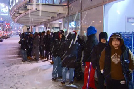 Uma fila de pessoas entusiásticas do Boxing Day, aguarda a abertura do espaço Best Buy, nas ruas Bay e Dundas, apesar da neve que caía na cidade de Toronto. CityNews.
