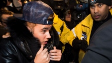 Justin Bieber cercado pelos Media e policiais, no momento em que ele se entregava à polícia da cidade de Toronto - 29 de janeiro, 2014. (Nathan Denette / THE CANADIAN PRESS)