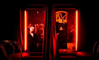 Um homem espreita para dentro de um bordel no Red Light District, em Amesterdão