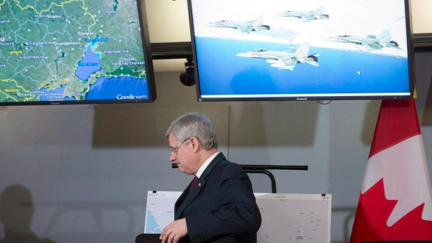 O primeiro-ministro canadiano, Stephen Harper deixa uma sala de reuniões, depois de anunciar que o Canadá vai enviar seis aviões de combate CF-18 para a Europa de Leste, como parte de uma missão da NATO. (The Canadian Press / Adrian Wyld)