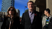 John Tory (centro) deixa uma mesa de voto em Toronto com a sua esposa Barbara Hackett, depois que ela registou o seu voto na eleição municipal de Toronto. 27 de outubro de 2014. (The Canadian Press / Chris Young)