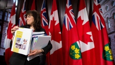 Auditor Geral, Bonnie Lysyk, segura uma cópia do seu relatório de 2014, numa conferência de imprensa em Toronto, na terça-feira, 9 de dezembro de 2014. (The Canadian Press / Nathan Denette)