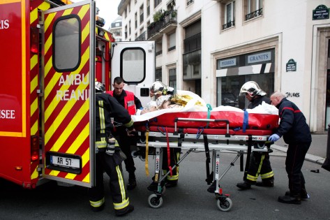 Uma pessoa ferida é transportada para uma ambulância, após um tiroteio no escritório do jornal satírico francês Charlie Hebdo, em Paris, em 7 de janeiro de 2015. The ASSOCIATED PRESS / Foto / Thibault Camus
