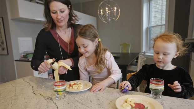 Kathy Burnett prepara um lanche para as suas filhas Claudia, ao centro, e Sabina, à direita, após a sua aula de ginástica, em Chicago - 29 de janeiro de 2015. (AP / M. Spencer Green)