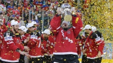 O guarda-redes do Canadá, Mike Smith, levanta o troféu após a sua equipa ter derrotado a Rússia no jogo de atribuição da medalha de ouro no Campeonato Mundial de hóquei no gelo, em Praga, República Checa, domingo, 17 de maio de 2015. (AP / Petr David Josek)