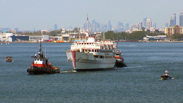Rebocadores removem o Captain John's do porto de Toronto, na sua última viagem para um porto no Lago Erie