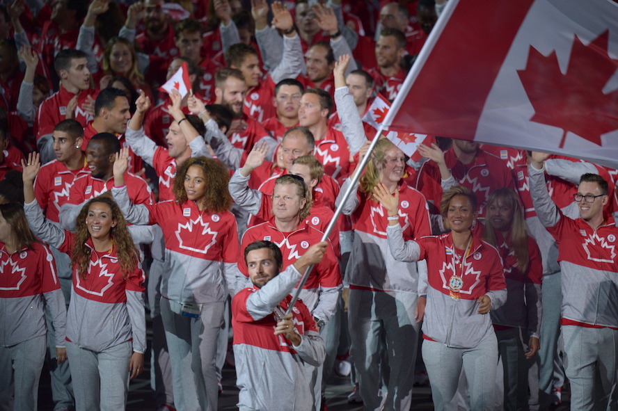 O canoísta canadiano, Mark Oldershaw, transporta a bandeira do Canadá ao lado de companheiros de equipa durante o desfile das nações na cerimónia de abertura dos Pan Am Games 2015 de Toronto no Rogers Centre na sexta-feira, 10 de julho de 2015. (The Canadian Press / Frank Gunn)
