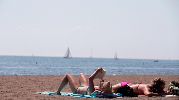 Pessoas leem enquanto apanham um banho de sol num dia de verão na Cherry Beach em Toronto - 23 de agosto de 2012. The Canadian Press / Michelle Siu