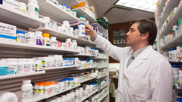 O farmacêutico Denis Boissinot verifica um frasco numa prateleira da sua farmácia, nesta foto de arquivo, em Quebec City. (THE Canadian Press / Jacques Boissinot)