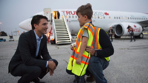 O líder do Partido Liberal Justin Trudeau conversa com Olivier Moreira, 6, que quebrou o braço a fazer piruetas, e o seu pai Fernando, antes de embarcar no seu avião para voar para Winnipeg, 29 de setembro, 2015, em Toronto. THE CANADIAN PRESS/Paul Chiasson