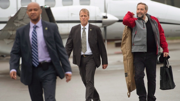 O líder do NDP Tom Mulcair, acompanhado por membros da sua equipa de segurança RCMP, caminha para o avião de campanha em Toronto - 29 de setembro de 2015. (The Canadian Press/Andrew Vaughan)