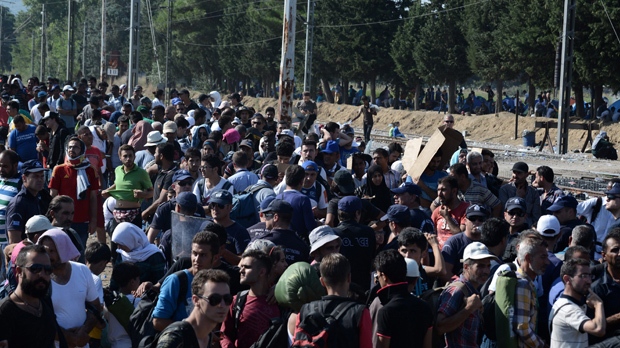 Policiais observam os imigrantes que esperam para passar as fronteiras da cidade grega do norte de Idomeni, para o sul da Macedónia, quinta-feira, 3 de setembro de 2015. (AP Photo / Giannis Papanikos)