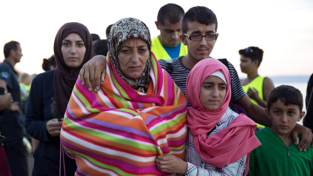 Uma família síria caminha depois de chegar com outros refugiados à costa da ilha grega de Lesbos, vindos da Turquia, num bote insuflável - 25 de setembro de 2015. (The Canadian Press/AP/Petros Giannakouris)