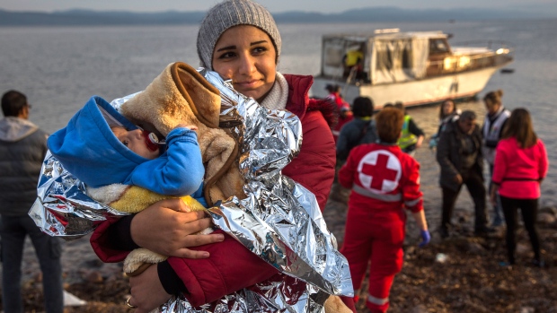 Uma mulher síria segura o seu bebé após a sua chegada num pequeno barco a partir da costa turca no Nordeste da ilha grega de Lesbos - 16 de novembro, 2015. (AP / Santi Palacios)
