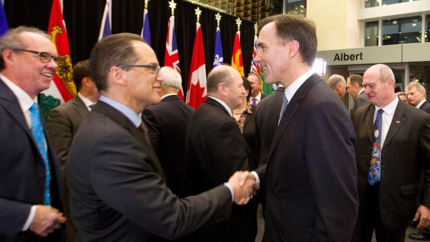 O ministro das Finanças Federal Bill Morneau, à direita, cumprimenta o ministro das Finanças de Alberta Joe Ceci, sob o olhar do ministro das Finanças de Manitoba Greg Dewar, logo após a conclusão de uma reunião dos ministros das finanças dos níveis federal, provincial e territorial em Otava - 21 de dezembro de 2015. (Fred Chartrand/The Canadian Press)