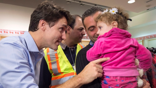 O primeiro-ministro canadiano Justin Trudeau fala com uma jovem ao cumprimentar uma família de refugiados sírios durante a sua chegada ao aeroporto International Pearson, em Toronto, na sexta-feira, 11 de dezembro de 2015. (Nathan Denette / The Canadian Press)