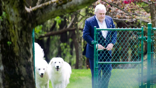 Conrad Black passeia com os seus dois cães quando chega à sua residência Bridle Path em Toronto, nesta foto de arquivo de 2012. (The Canadian Press / Nathan Denette)