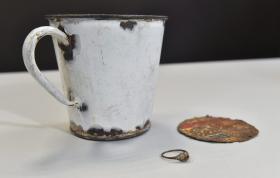 MUSEU DE AUSCHWITZ ENCONTRA JOIAS DE PRISIONEIRO EM FUNDO FALSO DE CANECA