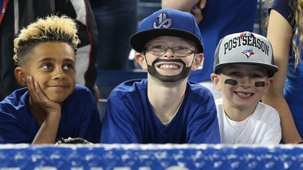Três jovens fãs dos Blue Jays assistem a um jogo em Toronto. (Tom Szczerbowski / Getty Images)