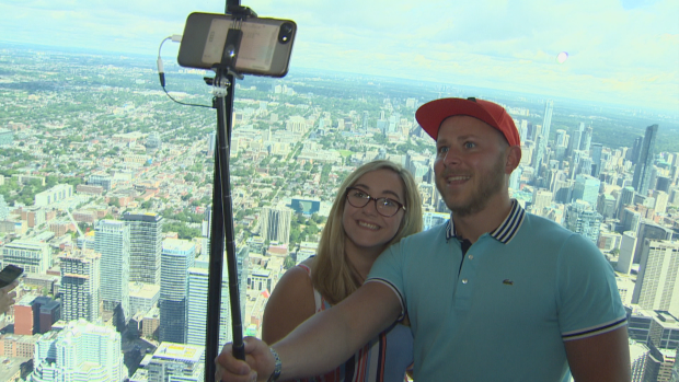 Visitantes da CN Tower tiram uma selfie em frente às novas áreas envidraçadas que foram reveladas na segunda-feira, dia 26 de junho de 2017. (CBC)