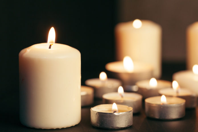 Many candles burning at night. Many candle flames glowing on dark background