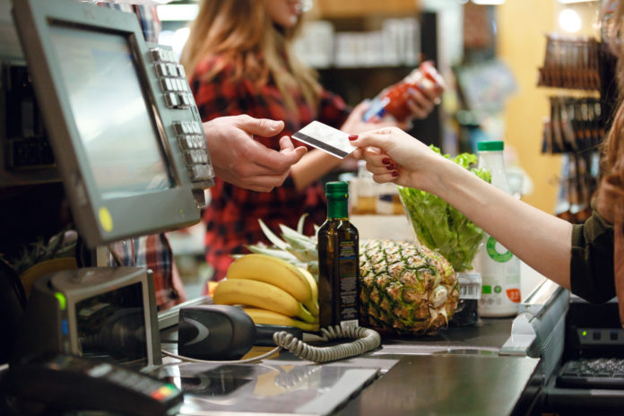 Cropped picture of young man gives credit card to cashier