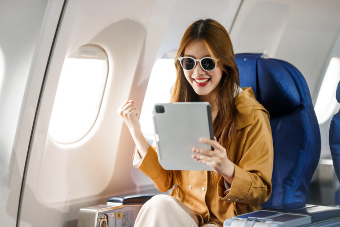 A young Asian woman, a passenger on an airplane, embarks on an e