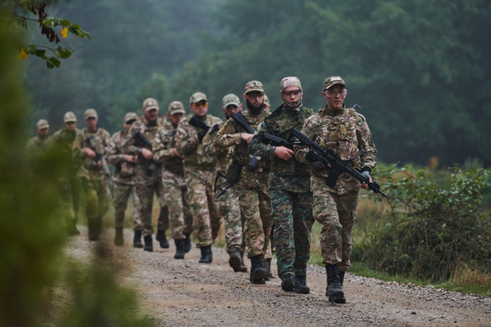 An elite military unit, led by a major, confidently parades through dense forest, showcasing precision, discipline, and readiness for high-risk operations