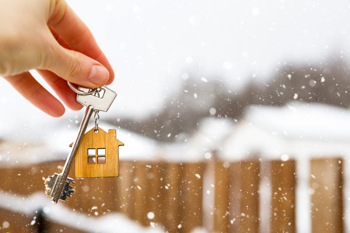 Hand with a Key of the house in winter in the snow. Background o