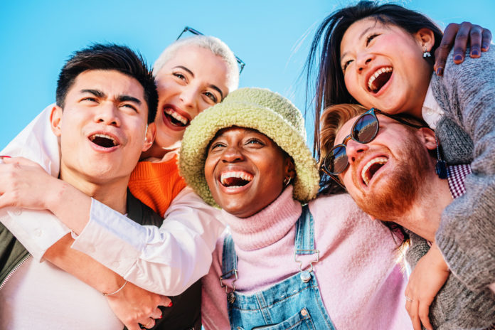 Multiracial young people laughing out loud on a sunny day enjoying vacation together.