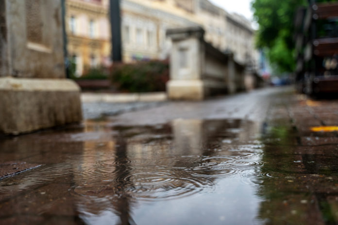 Rain in the city, drops are falling. Close-up of the sidewalk. U