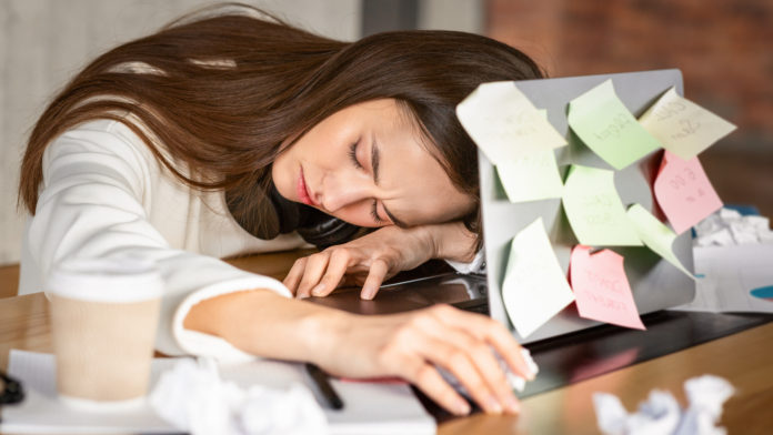 Young woman sleeping in front of laptop