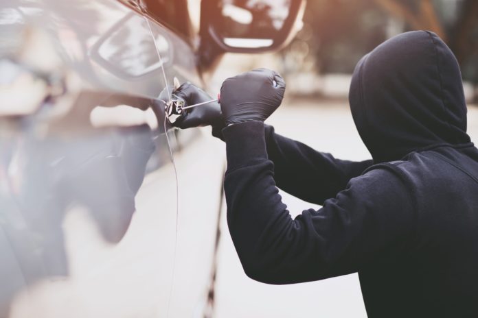 hooded-figure-manipulating-car-door-lock-2026-03-09-08-15-01-utc