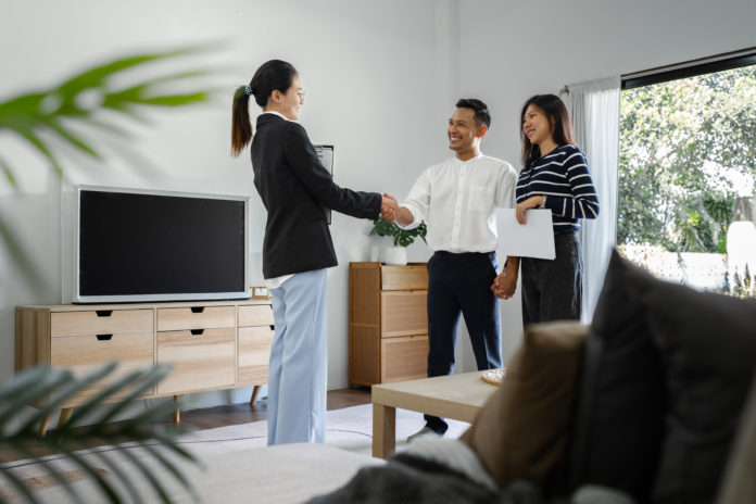 Young happy smiling couple read agreement with realtor and looking through the contract of real estate sale going to signing a deal