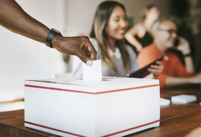 Black man casting his vote to a ballot box
